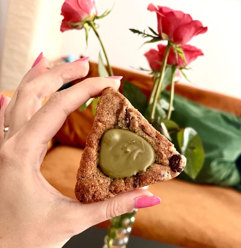 woman holding pistacio Trinity cookie. roses in the background